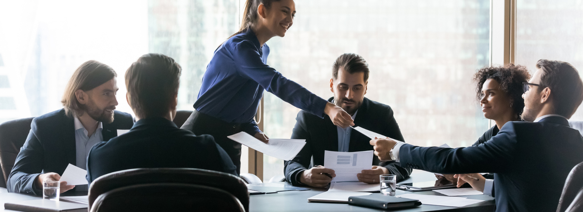 Business woman passes out papers in meeting