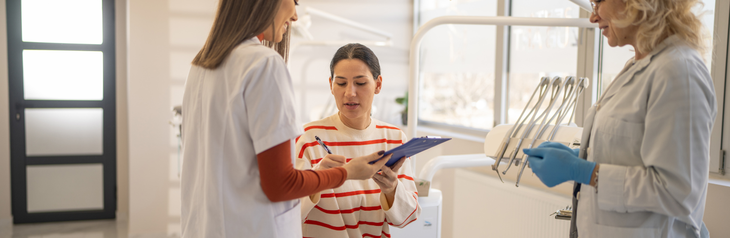 woman signs insurance paperwork at dentist