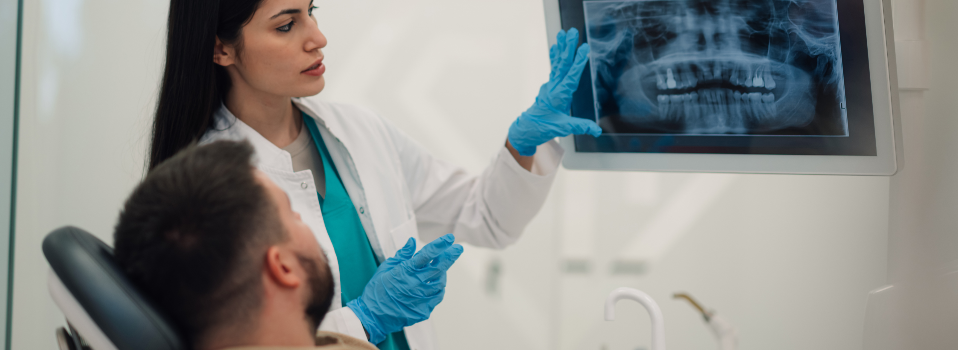 Female dentist explaining radiography to a male patient sitting in a dental chair