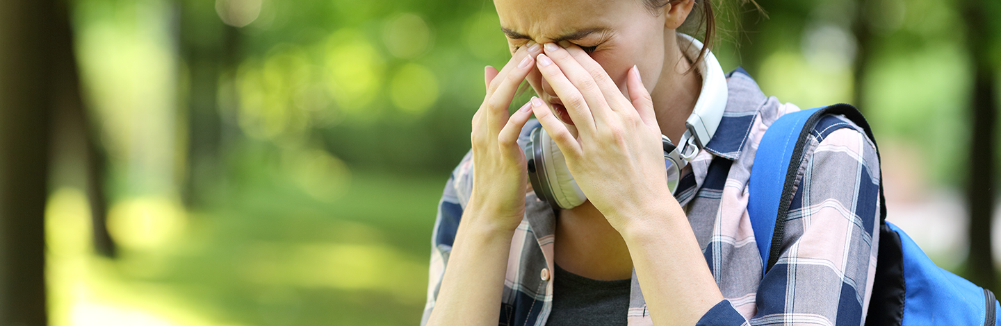female student rubs eyes while outside from allergies