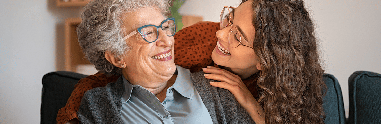 elderly woman wearing glasses smiles with young woman