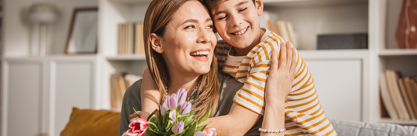 son hugs mother after giving her flowers