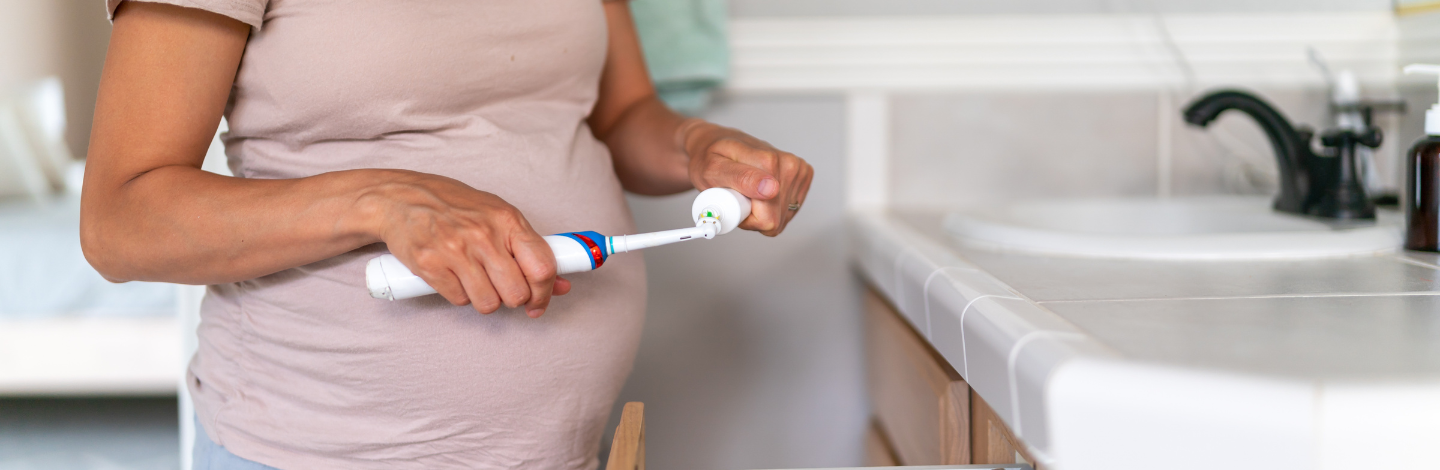 pregnant woman puts toothpaste on toothbrush