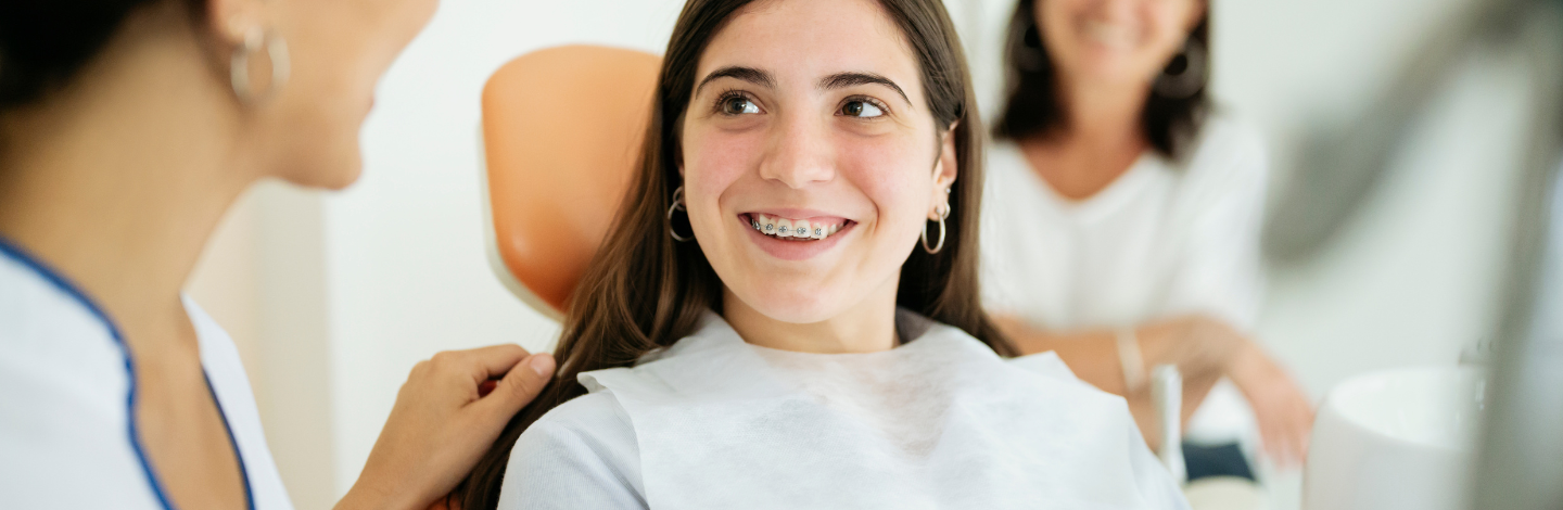teenage girl smiles at dentist with braces on