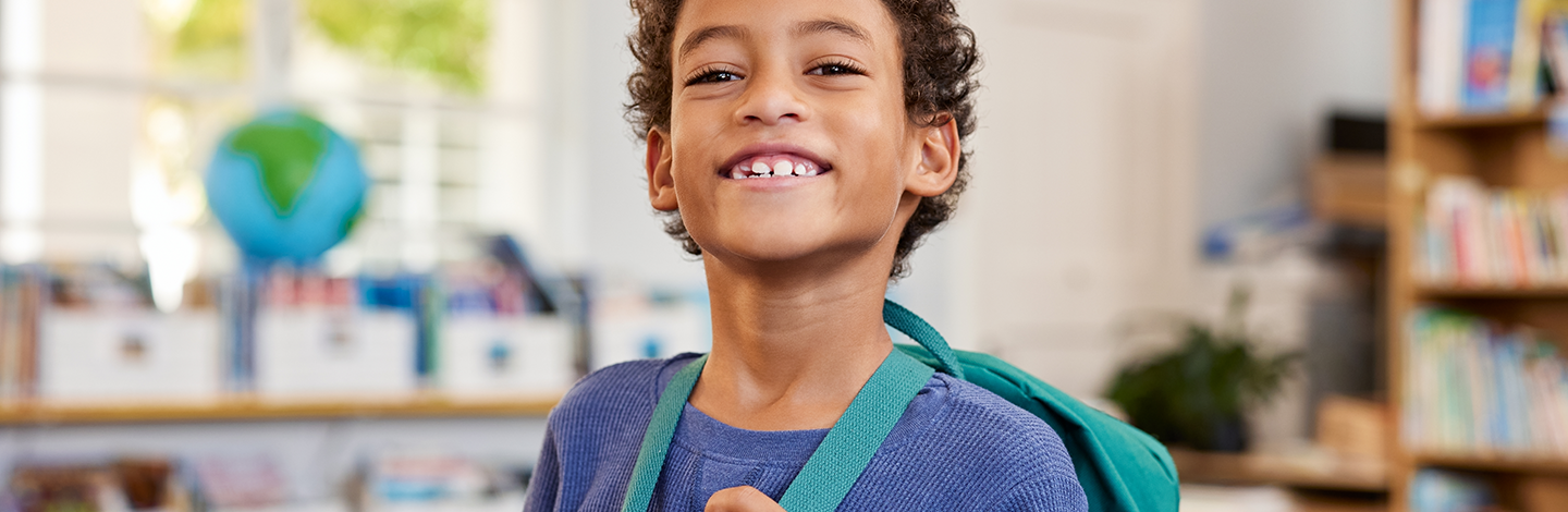 Child smiles with backpack on