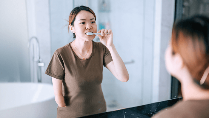 woman-brushing-teeth-in-mirror-1200x683 woman-brushing-teeth-in-mirror-1200x683