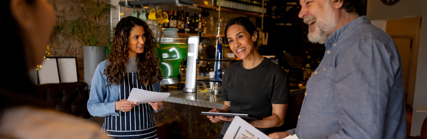 Happy cafe manager talking to a group of employees in a staff meeting and smiling