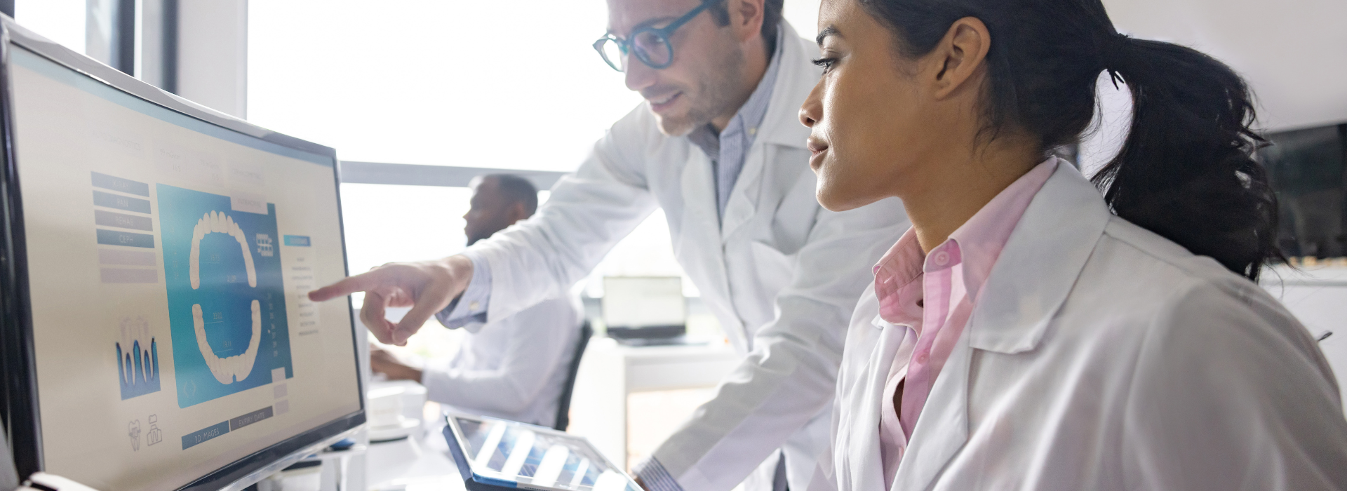 dental researchers look at computer screen with 3d modeling of teeth