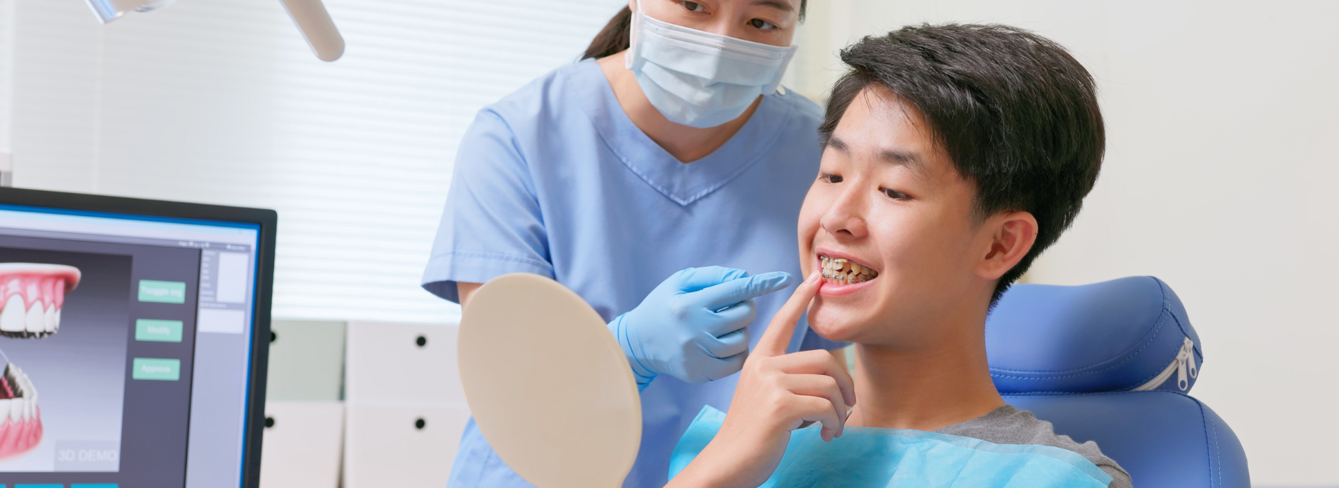 dentist talks to a male teenage patient about metal braces while he looks at mirror