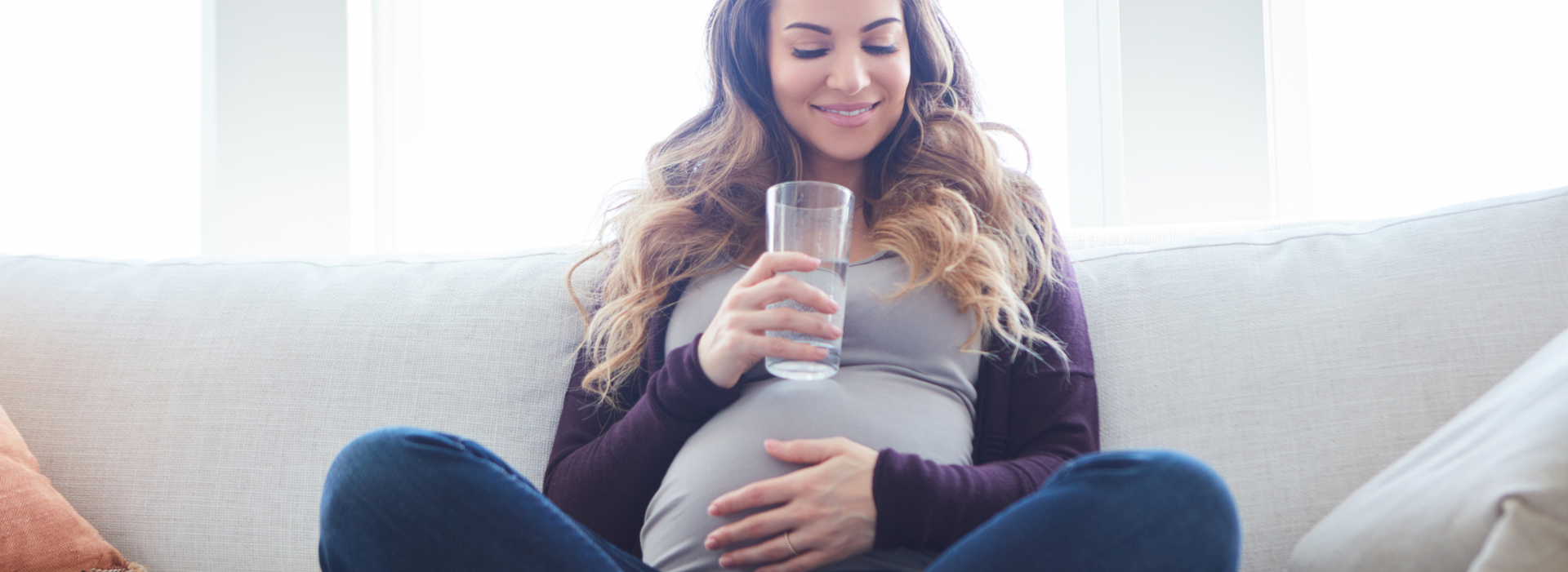 Pregnant woman holds glass of water while smiling