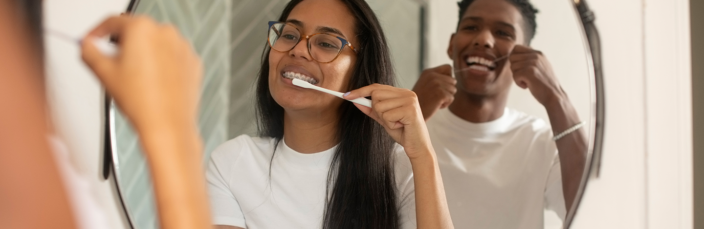 couple brushing and flossing their teeth