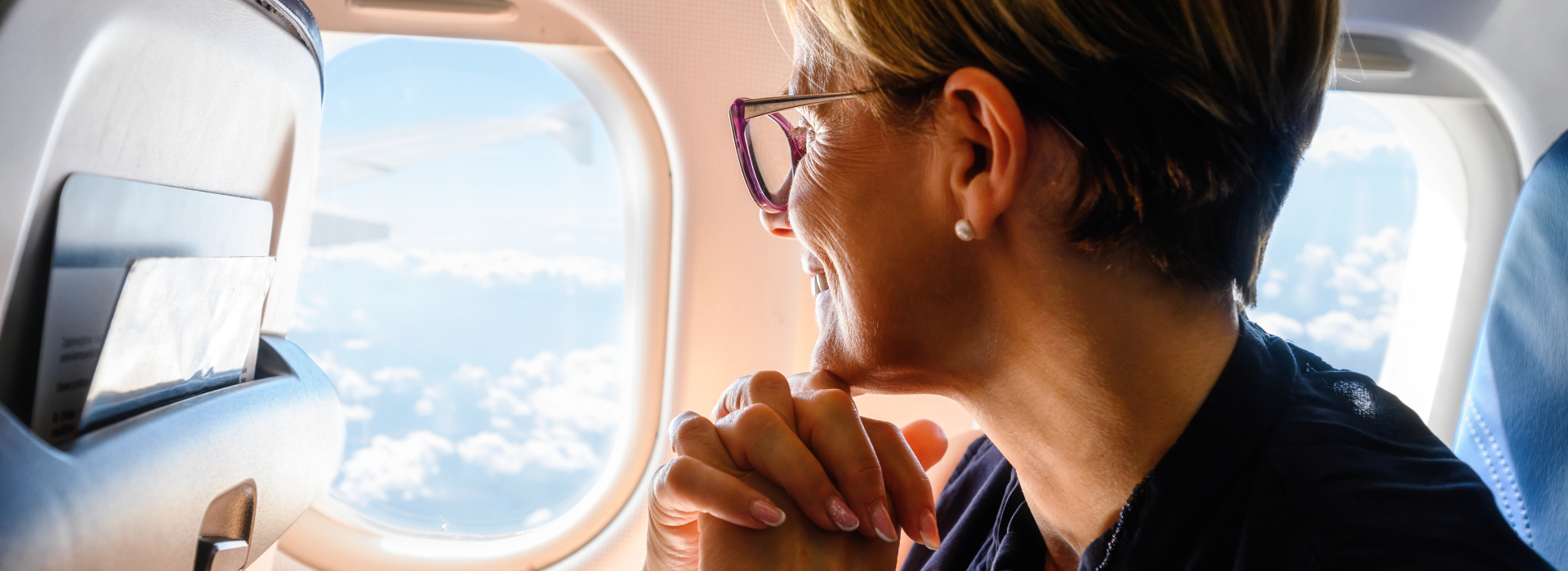 woman wears glasses while looking out airplane window